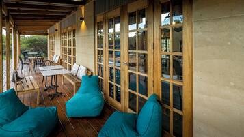 An outdoor patio with wooden furniture and large windows.
