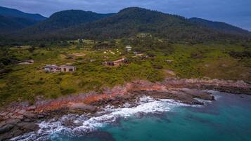 A coastal property with multiple buildings, a rocky shoreline, and lush greenery.