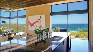 A modern kitchen with a large island, a dining area, and a view of the ocean.