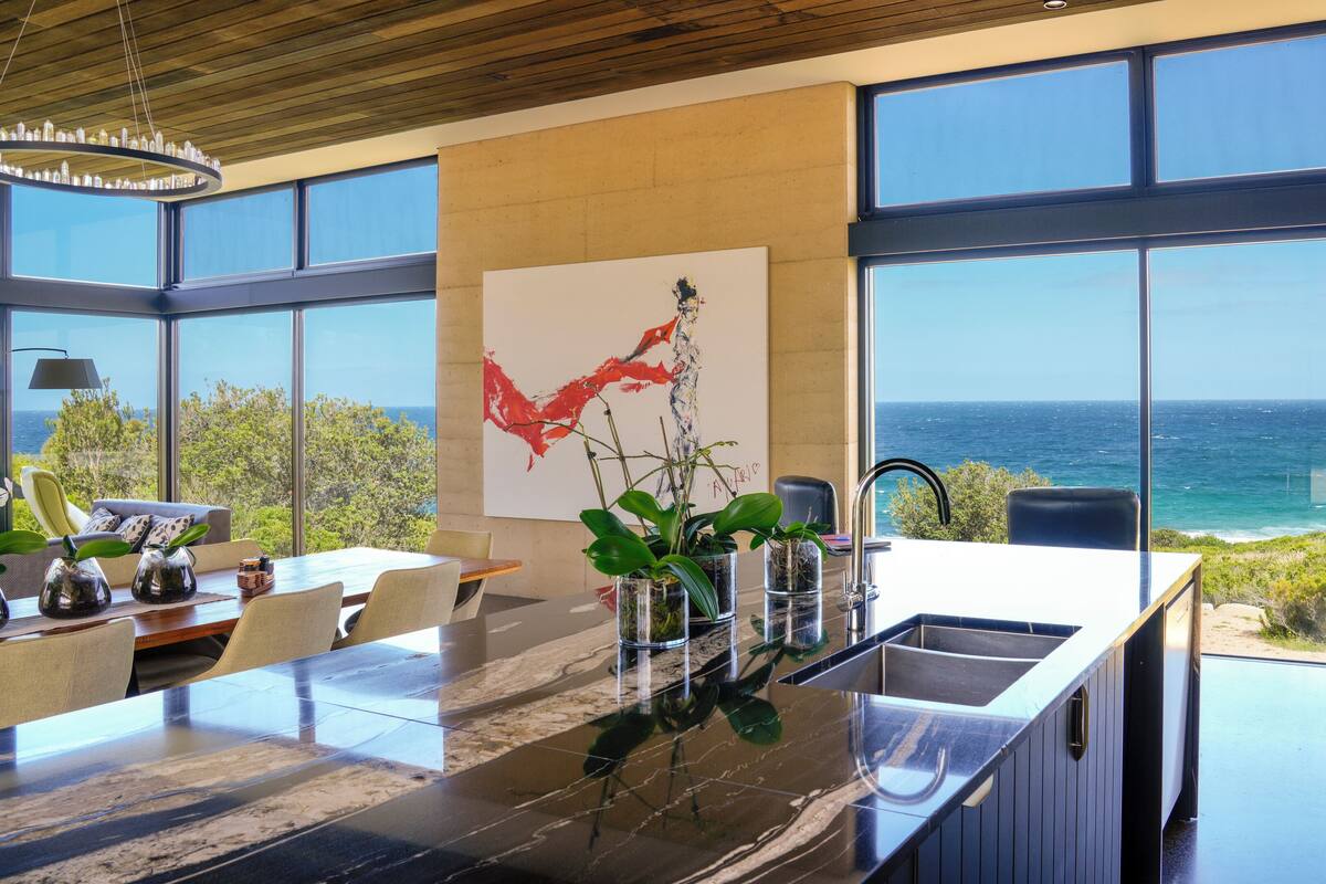 A modern kitchen with a large island, a dining area, and a view of the ocean.