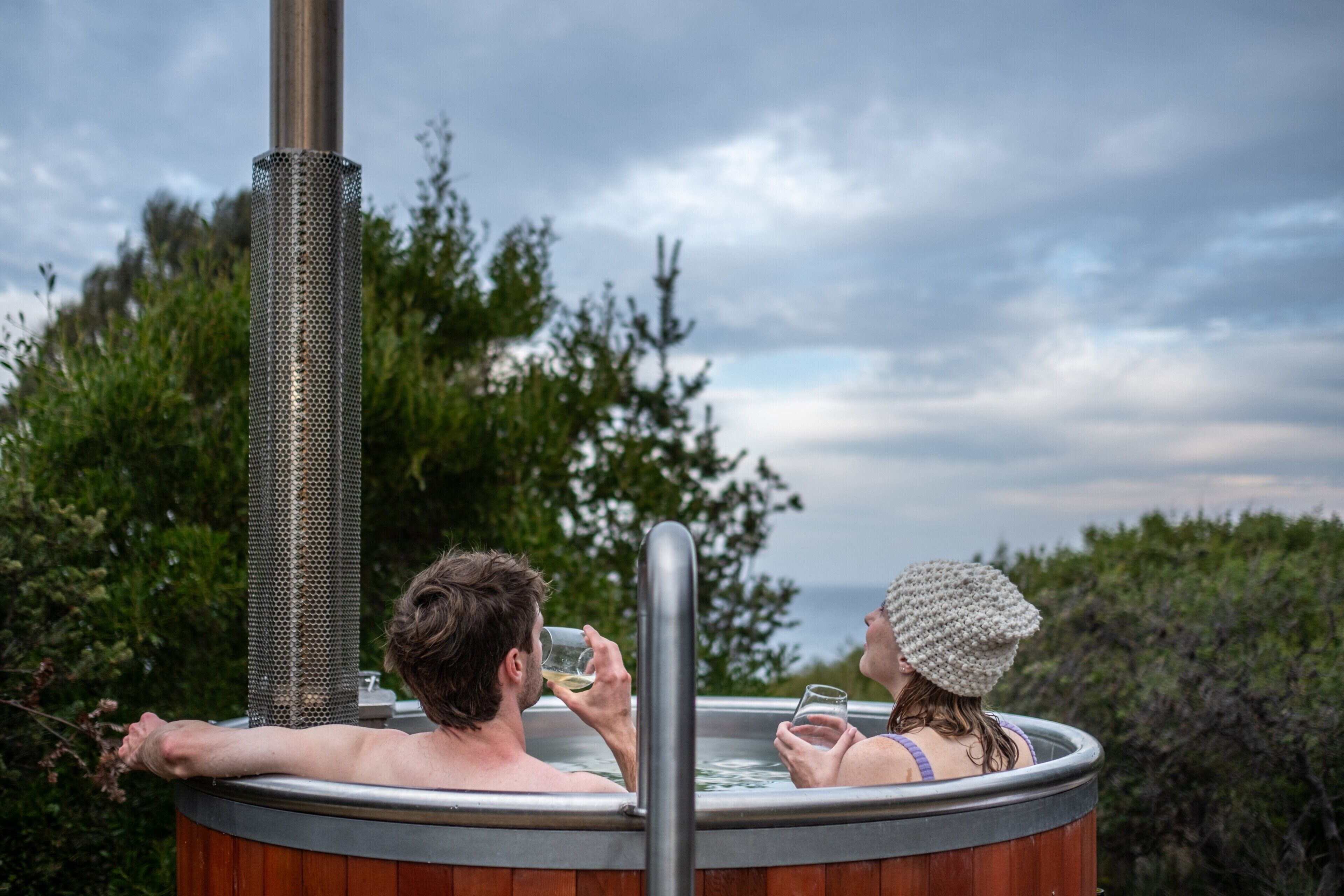 Ein Whirlpool mit einem Metallschornstein, umgeben von viel Grün und einem bewölkten Himmel.