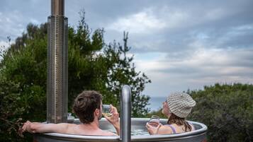 Ein Whirlpool mit einem Metallschornstein, umgeben von viel Grün und einem bewölkten Himmel.