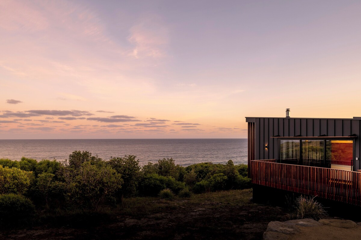 Un bâtiment moderne offrant une vue sur la mer au coucher du soleil.