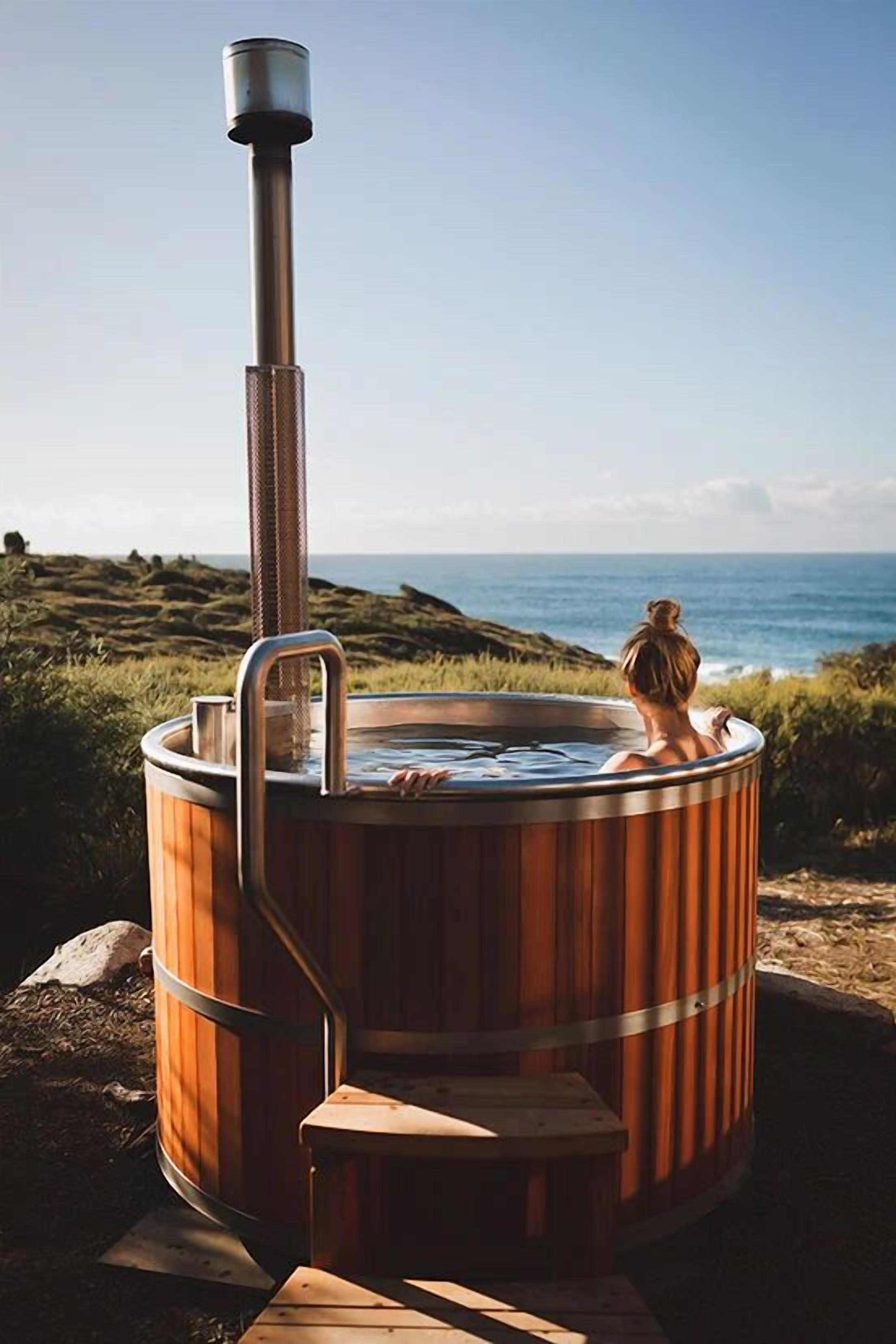 Una banyera de fusta amb un tub d'escapament metàl·lic, situada sobre un terreny rocos amb vista a l'oceà.