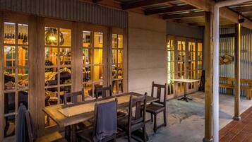 A wooden table and chairs set in a room with large windows and a reception area visible through the glass doors.