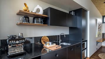Una cocina moderna con encimera negra, cafetera, fregadero y tabla de cortar de madera.