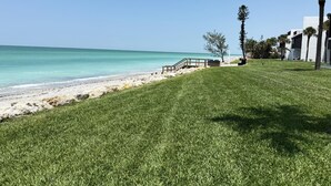 A grassy area with a wooden walkway leading to a beach. - Direct Gulf Views - Beachfront Stay at Tamarind (Englewood)