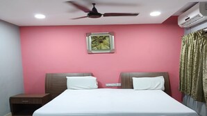 A bedroom with a bed, two nightstands, a ceiling fan, an air conditioner, and a framed picture on the wall. - Elite Residency Pallavaram (Chennai)