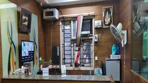 A reception desk with a computer monitor, a telephone, and a water dispenser. - Elite Residency Pallavaram (Chennai)