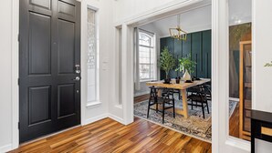 A dining area with a wooden table and chairs, a black door, and a view into another room with a dark wall and a plant. - Resort-style, Frisco Getaway, Saltwater Pool, FREE Heated Spa (Frisco)