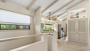 A modern kitchen with a central island, a dining area with a table and chairs, and a view of the outdoors through large windows.