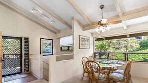 A dining area with a round table and wicker chairs, a ceiling fan, and framed artwork on the walls.