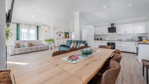 A modern living space with a dining area, kitchen, and seating area. - Quinta Ribeira do Arade (São Bartolomeu de Messines)