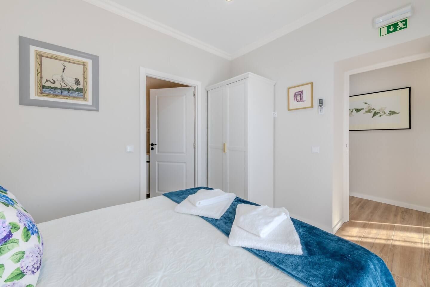 A hotel room with a bed, a door leading to a bathroom, and a framed picture on the wall.
