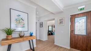 A hallway with a wooden console table, framed artwork, and a wooden door. - Quinta Ribeira do Arade (São Bartolomeu de Messines)