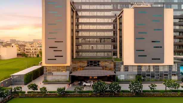 A modern building with a glass facade, multiple floors, and a covered entrance area.