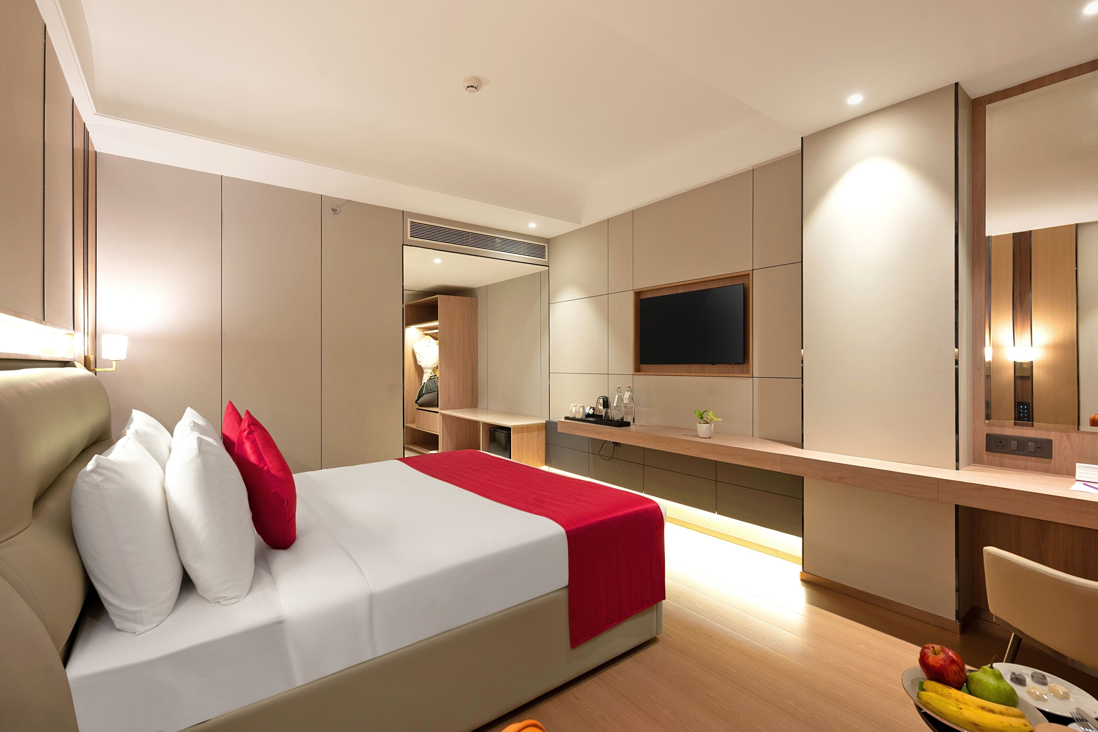 A hotel room with a bed, a desk, a TV, and a mirror.