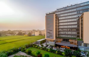 Un edificio moderno con techo plano y ventanas amplias, rodeado por un jardín cuidado y un campo verde.