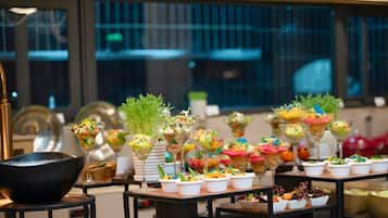 A buffet table with various food items and a large black bowl on the left.