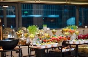 Ein Buffet mit verschiedenen Speisen und einer großen schwarzen Schüssel auf der linken Seite.