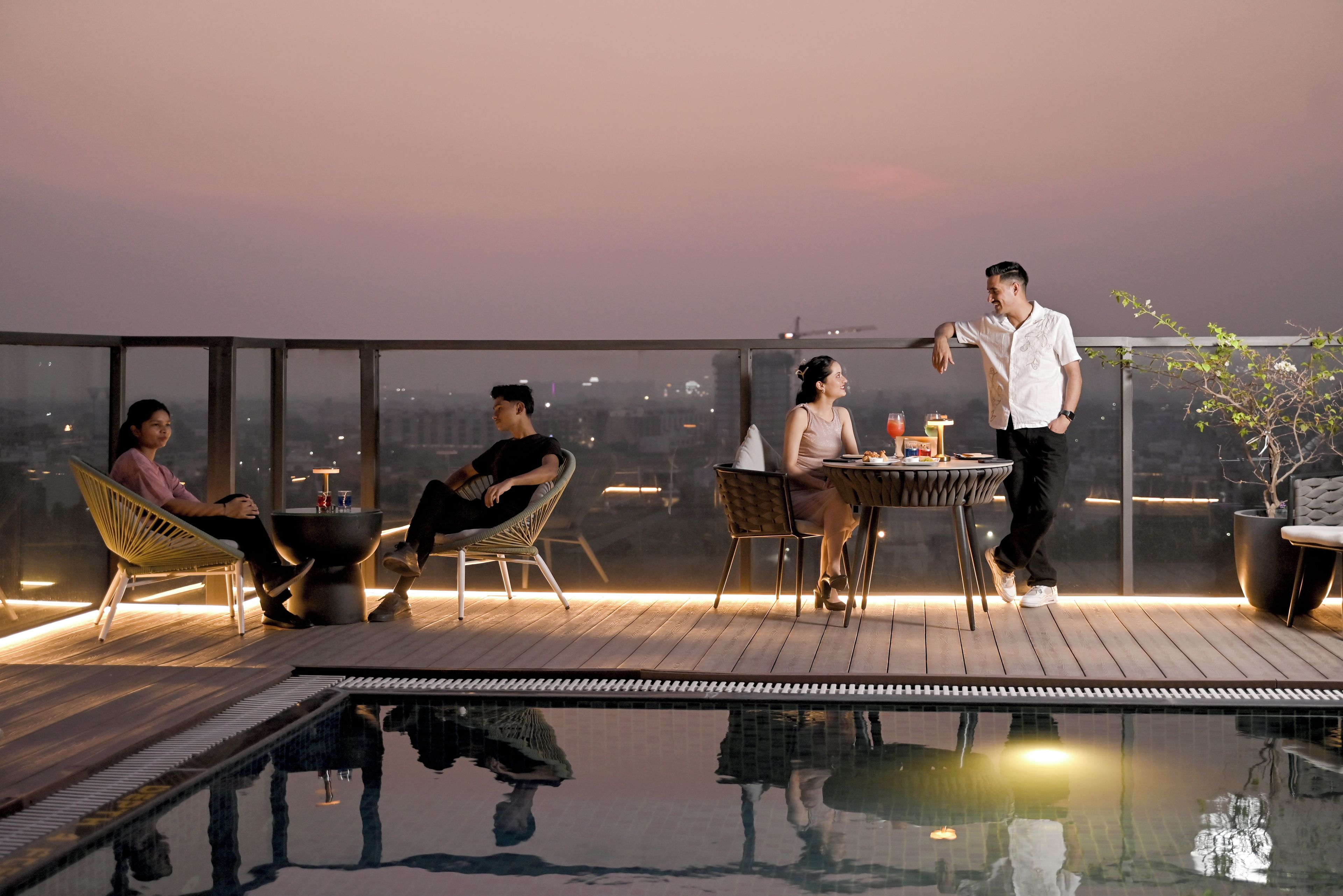 A rooftop terrace with a pool, seating, and a table with drinks.
