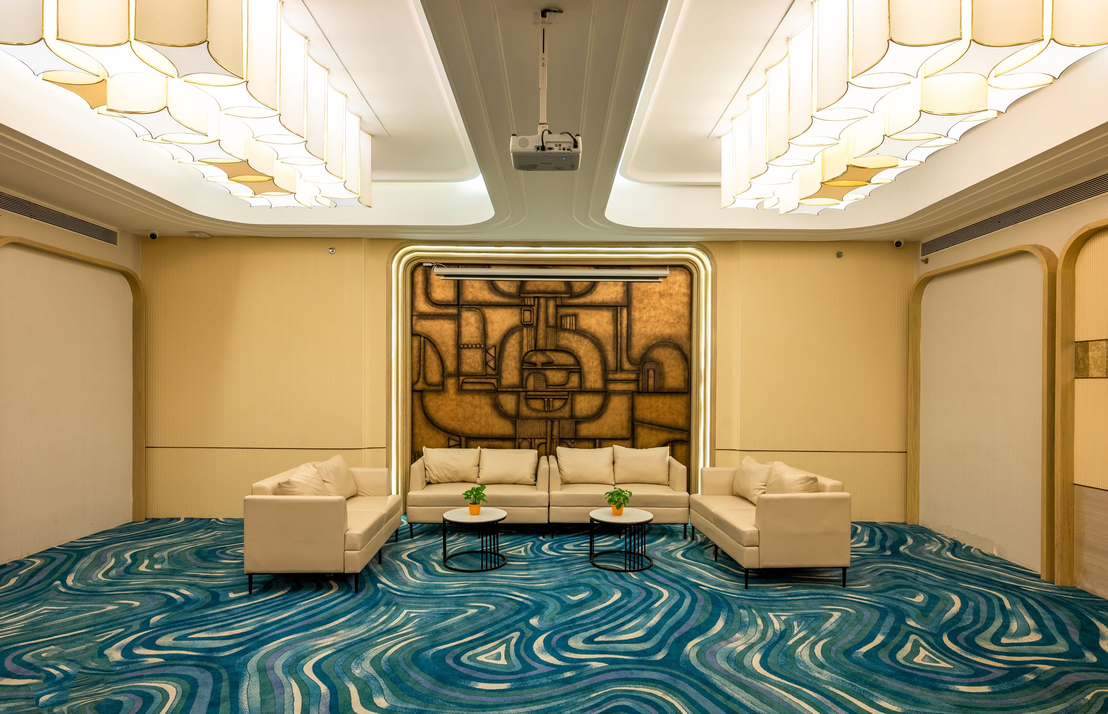 A conference room with a modern design, featuring a large sofa set, two small tables, and a decorative wall panel.
