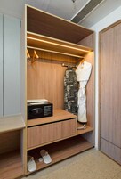 A walk-in closet with wooden shelving, a hanging rack, a radio, and a pair of slippers.