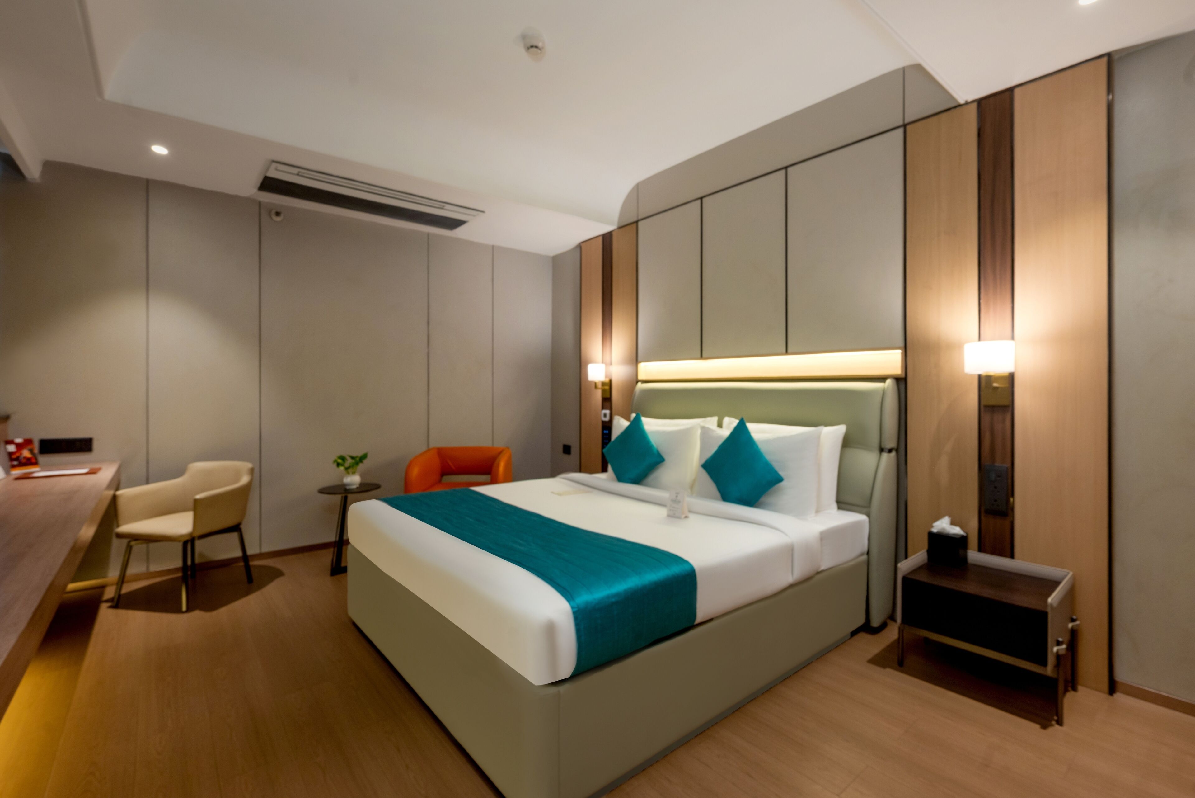 A modern hotel room with a large bed, a desk, and a chair.