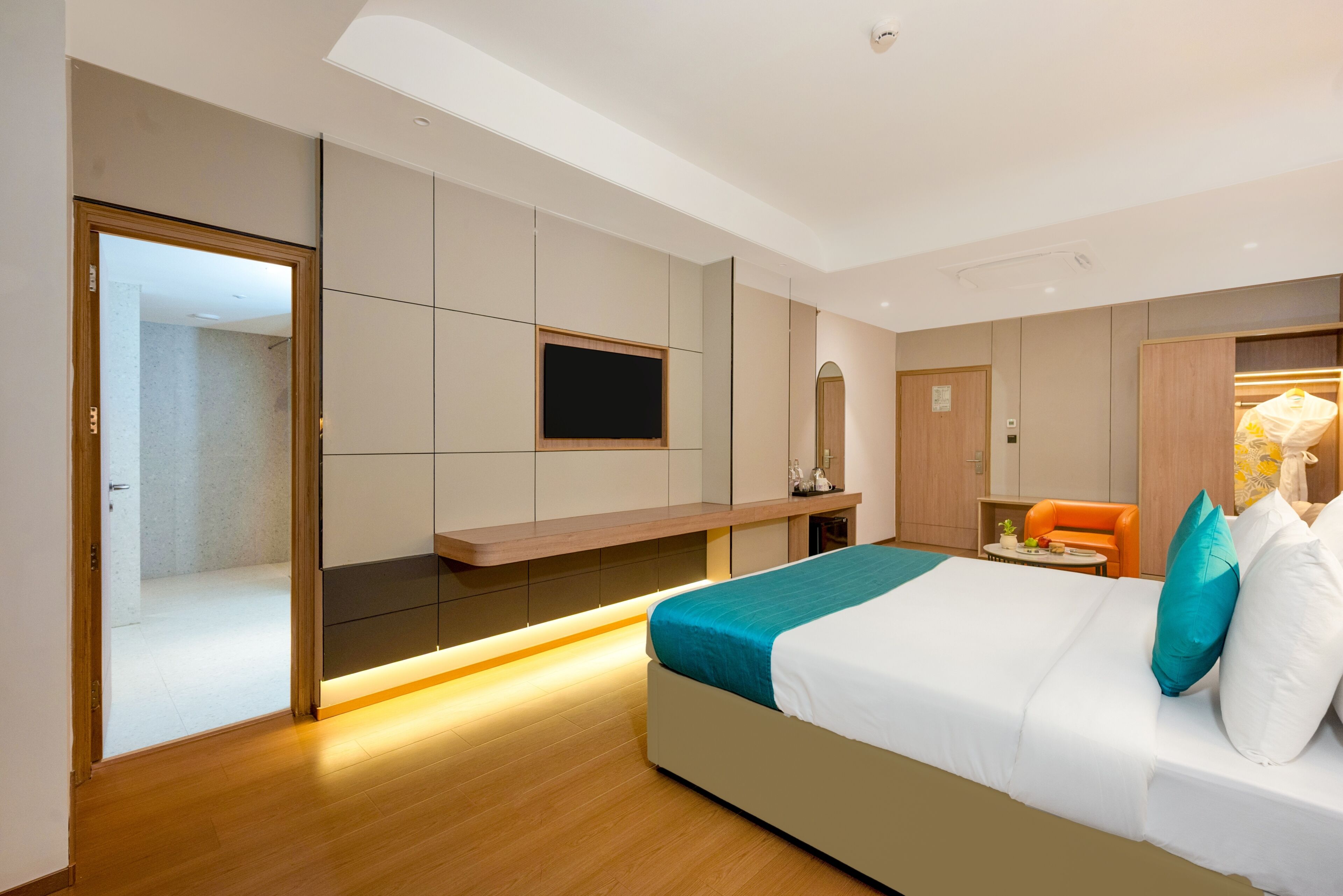 Una habitación de hotel moderna con cama, televisión, zona de estar y armario.