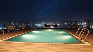A rooftop pool with a city view at night. - Orchid Hotel Chandigarh,Zirakpur (Dera Bassi)