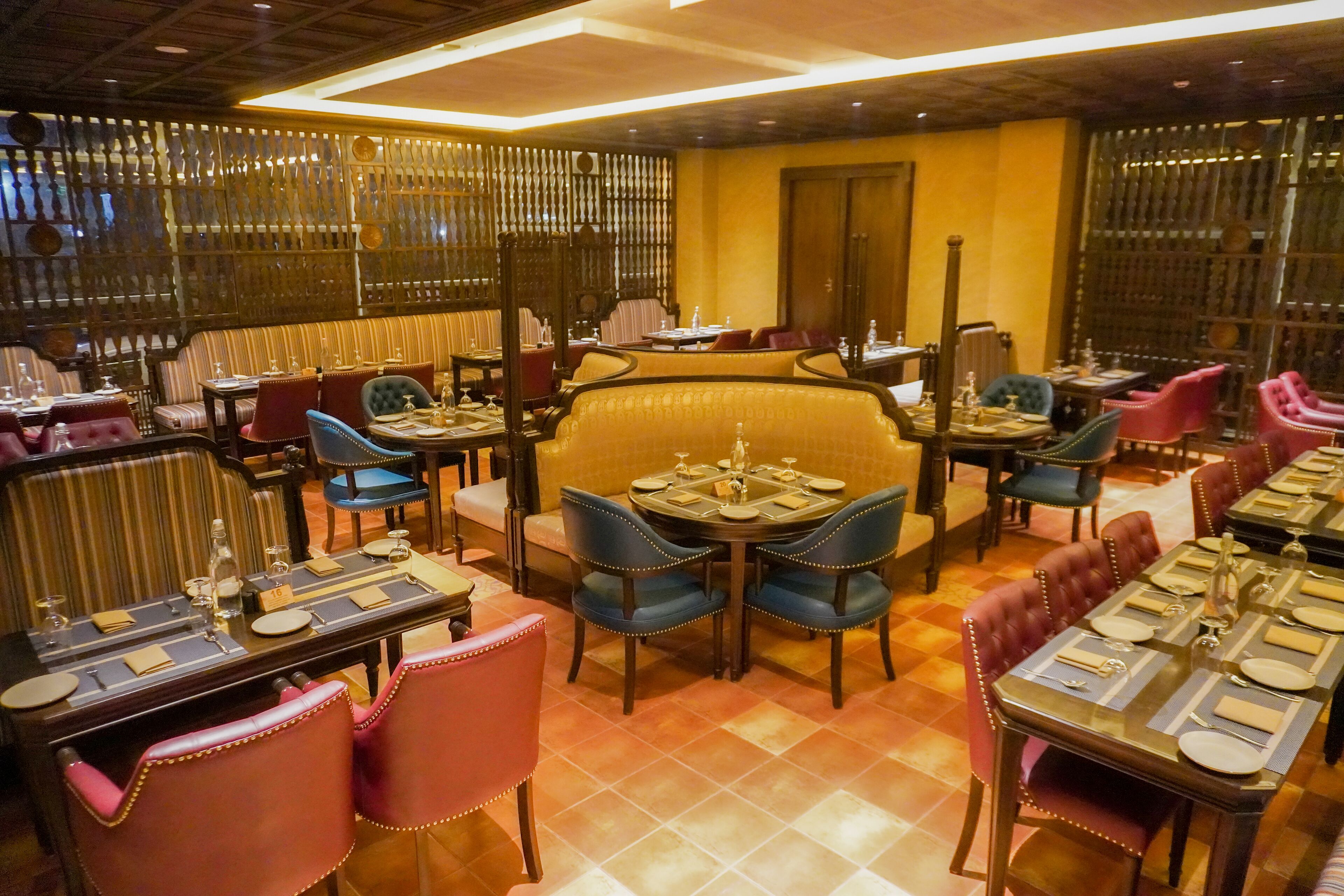A restaurant with multiple dining tables and chairs, some with pink and blue upholstery.