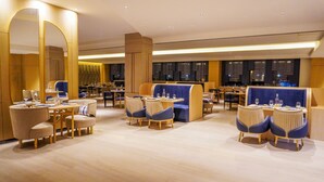 A modern hotel lobby with seating areas, tables, and a large mirror.
