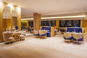 Un moderno vestíbulo de hotel con zonas de estar, mesas y un espejo grande.