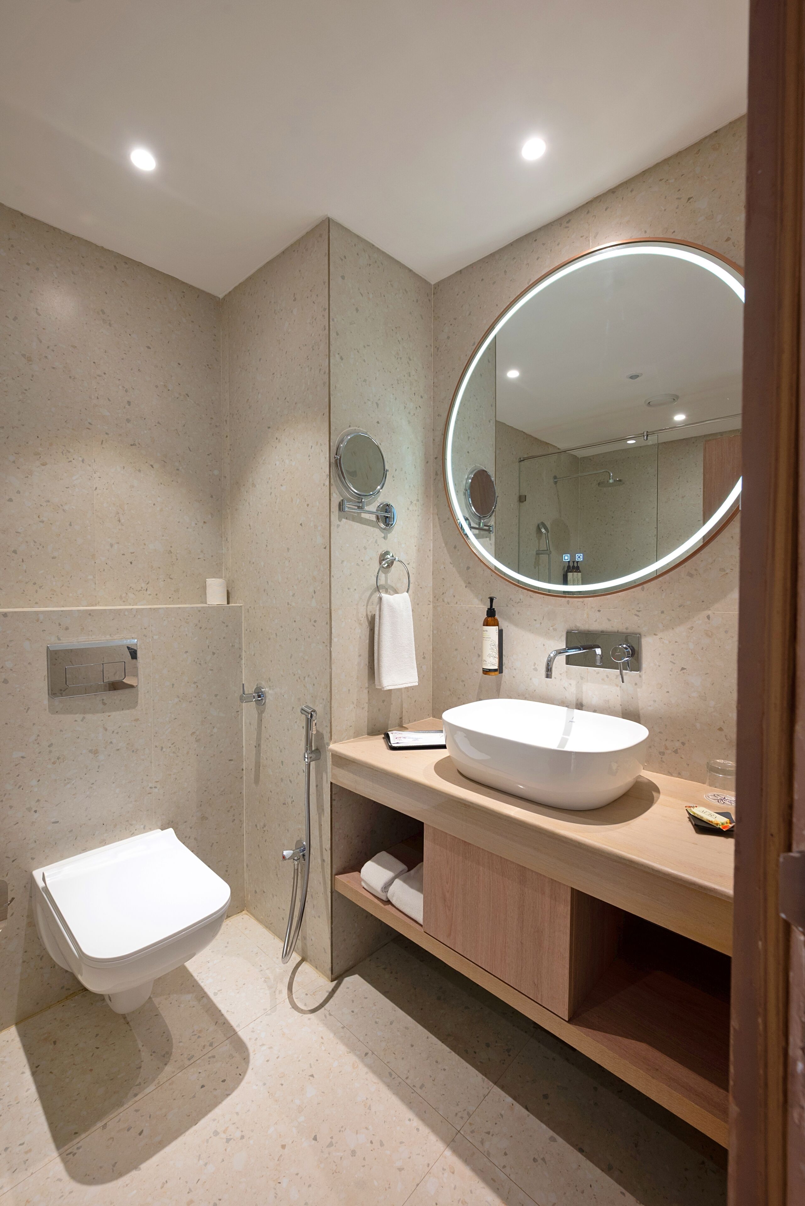 Un baño moderno con inodoro independiente, lavabo con espejo y zona de ducha.