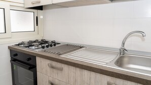A kitchen with a gas stove, stainless steel sink, and wooden cabinets.