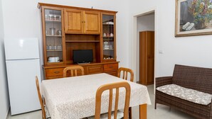 A dining area with a table, chairs, a television, and a cabinet with glass doors.