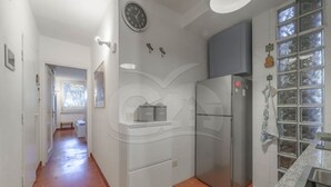 A kitchen with a refrigerator, a clock, and a window with a view.