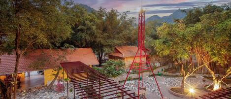 Un patio con una pérgola, una torre roja y edificios tradicionales.
