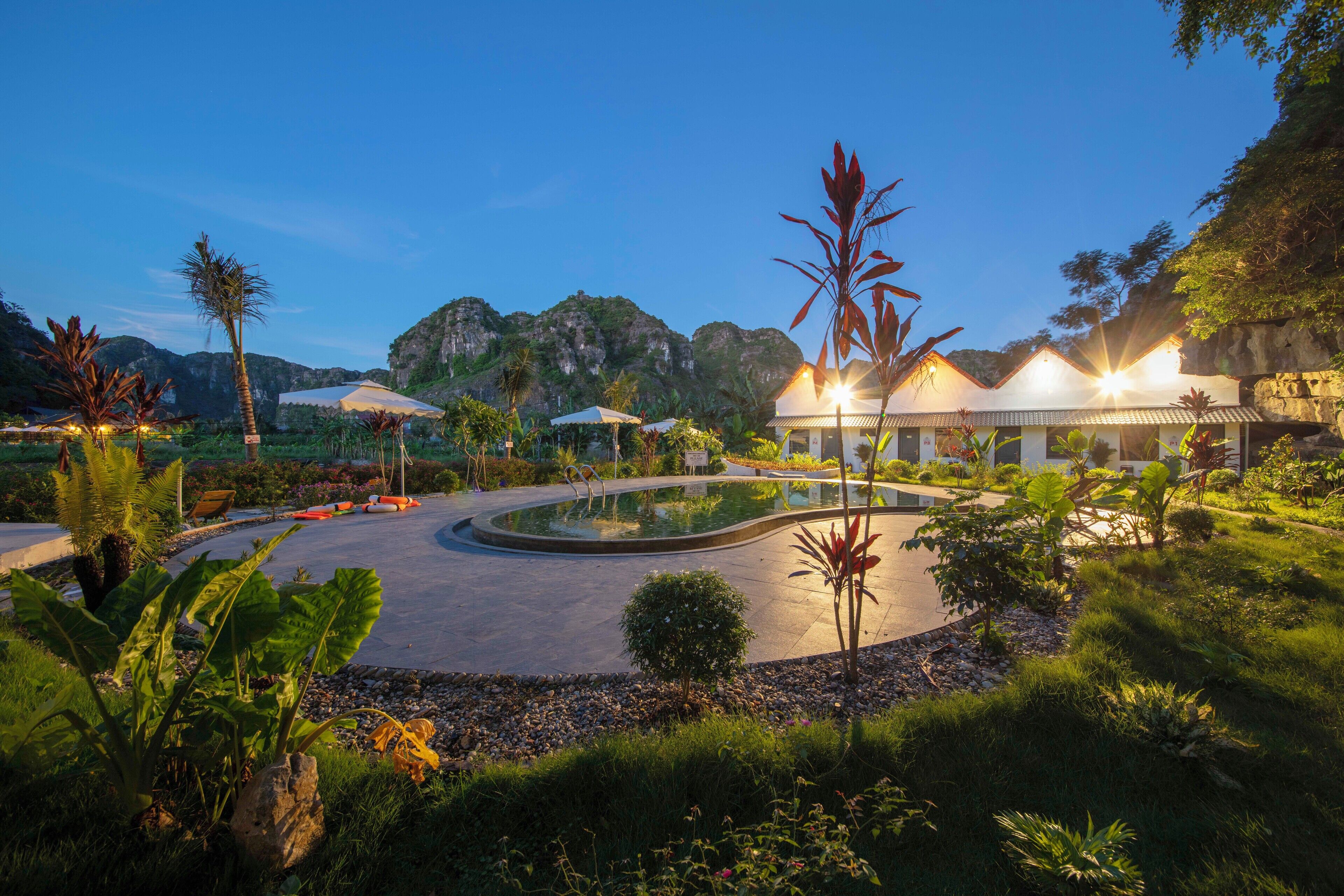 A resort with a pool, palm trees, and a mountain backdrop.