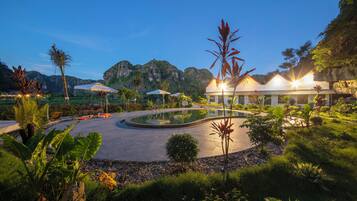 A resort with a pool, palm trees, and a mountain backdrop.