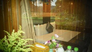 A room with a bed, a window, and a table with a vase and bottles.