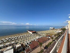 Een kusthotel met zitplaatsen aan het strand en uitzicht op zee.