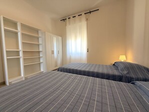 Een slaapkamer met een bed, een kledingkast en een raam met gordijnen.