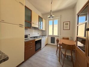 Een compacte keuken met een eethoek, voorzien van een kookplaat, magnetron en spoelbak.