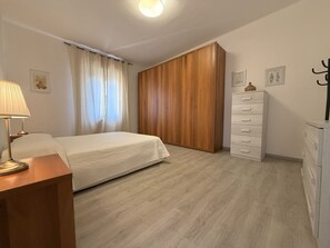 Et soveværelse med seng, natbord, kommode og garderobeskab.