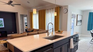A modern kitchen with a central island, black cabinetry, and a built-in dishwasher. - Your Perfect Home Away From Home · Owasso, OK (Owasso)