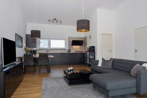 Una sala de estar moderna con un sofá gris, una mesa de centro y un televisor.