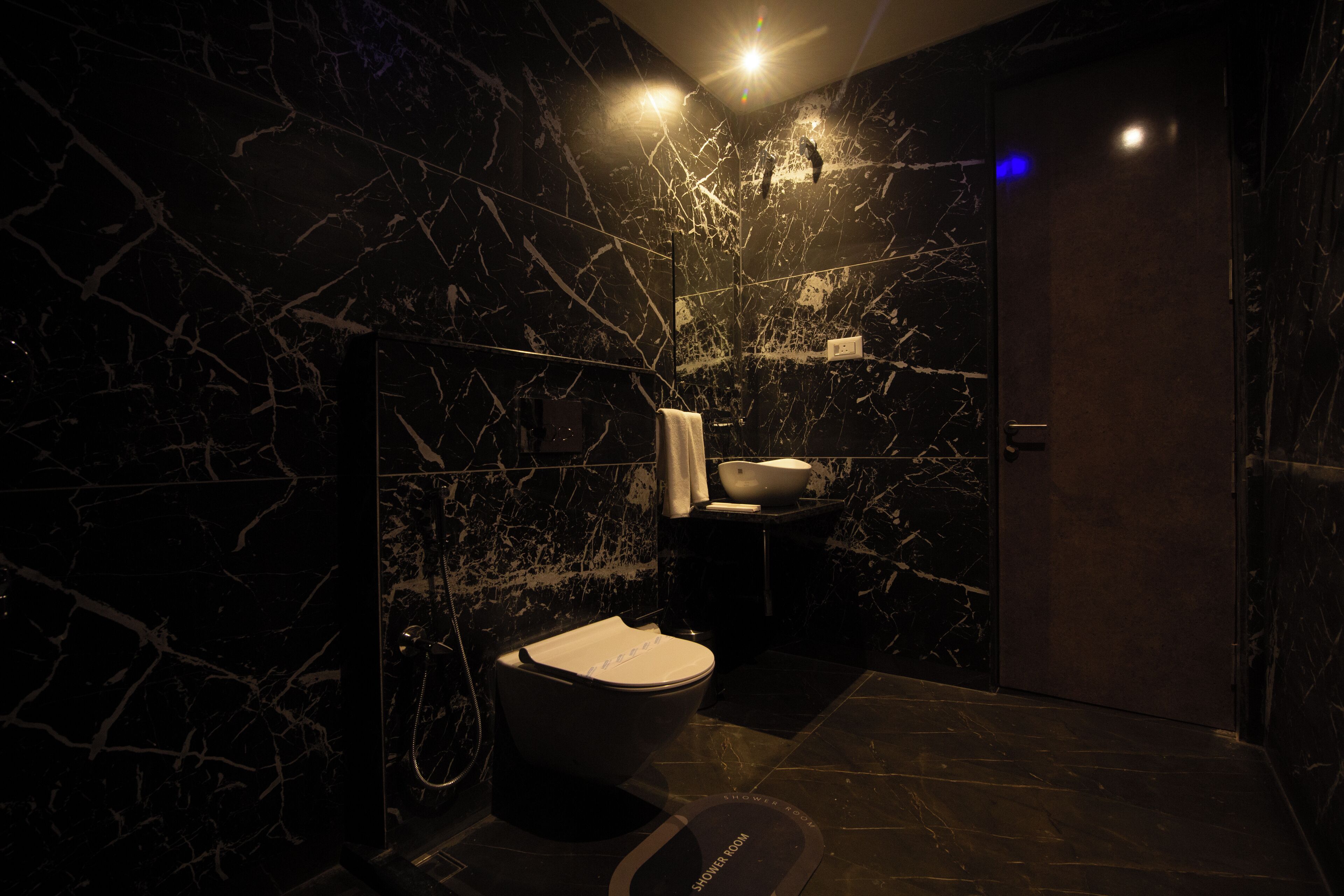 A modern bathroom with a marble wall, a toilet, a sink, and a shower area.