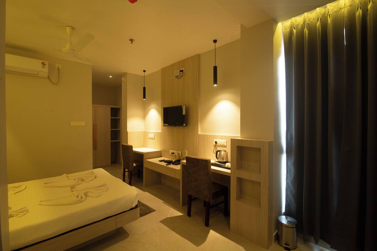 Una habitación de hotel con cama, escritorio, silla y televisión instalada en la pared.