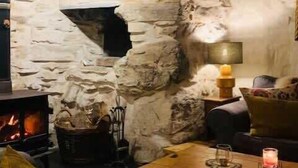A cozy room with a stone fireplace, a sofa, and a coffee table. - Secluded Mountain Stay - Stunning Views of Eryri (Dolgellau)